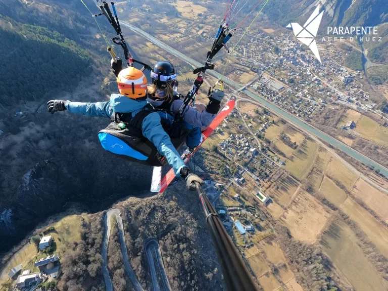 Vol en parapente biplace au-dessus de la vallée de Bourg d'Oisans avec un autre parapente en contrebas. Photo vol parapente Alpe d’Huez