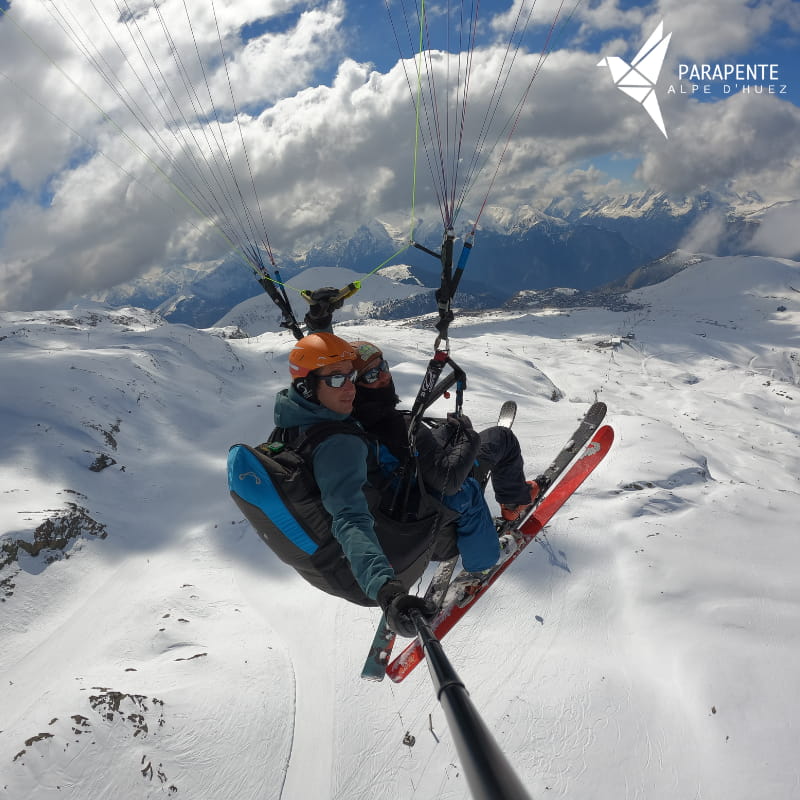 Vol en parapente au-dessus du domaine skiable de l'Alpe d’Huez avec vue panoramique sur la station et le massif des Écrins.