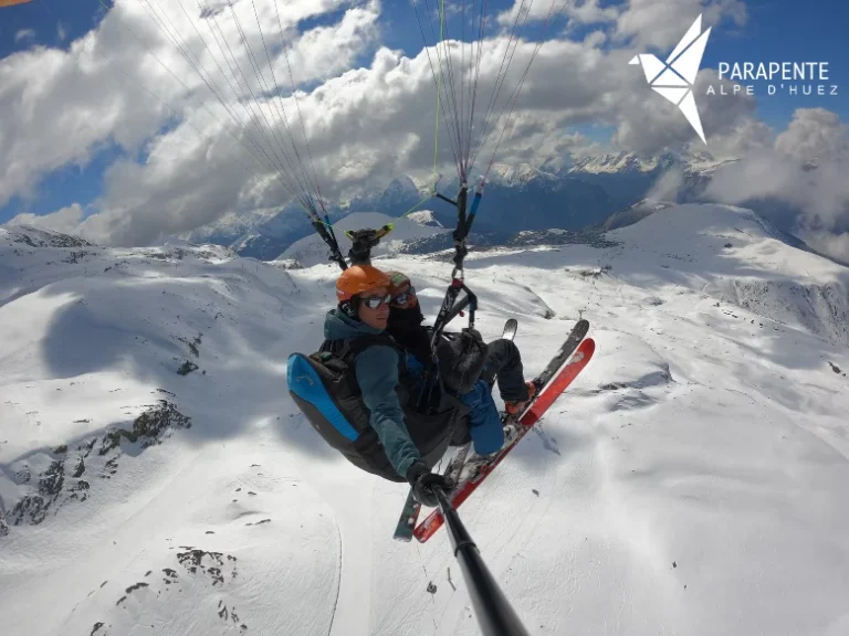 Tandem paragliding above Alpe d’Huez, soaring over the ski slopes with a view of the Oisans mountains