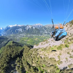 Vol parapente biplace face à la vallée de l’Oisans en été depuis l’Alpe d’Huez